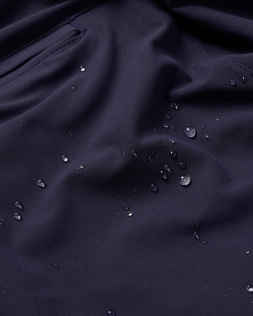 A close up detailed shot of water droplets beading on navy material to illustrate the trouser's water repellency